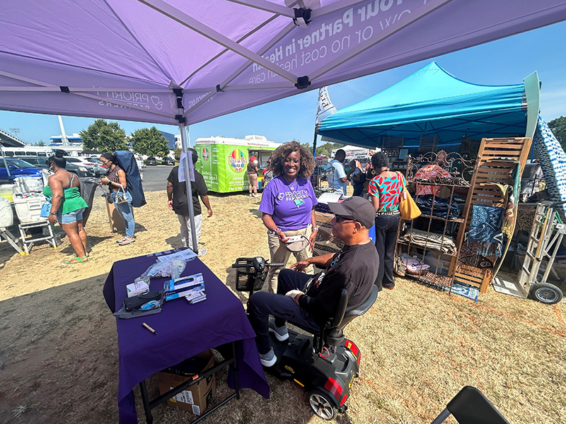 Dr. Everett standing by the Priority Partners table at the Kunte Kinte festival