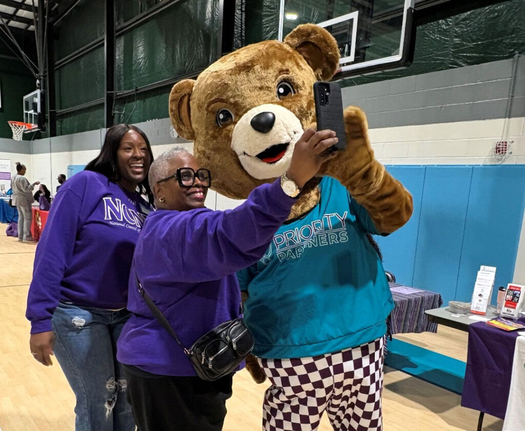 Cubby, the Priority Partners mascot posing for a picture with people