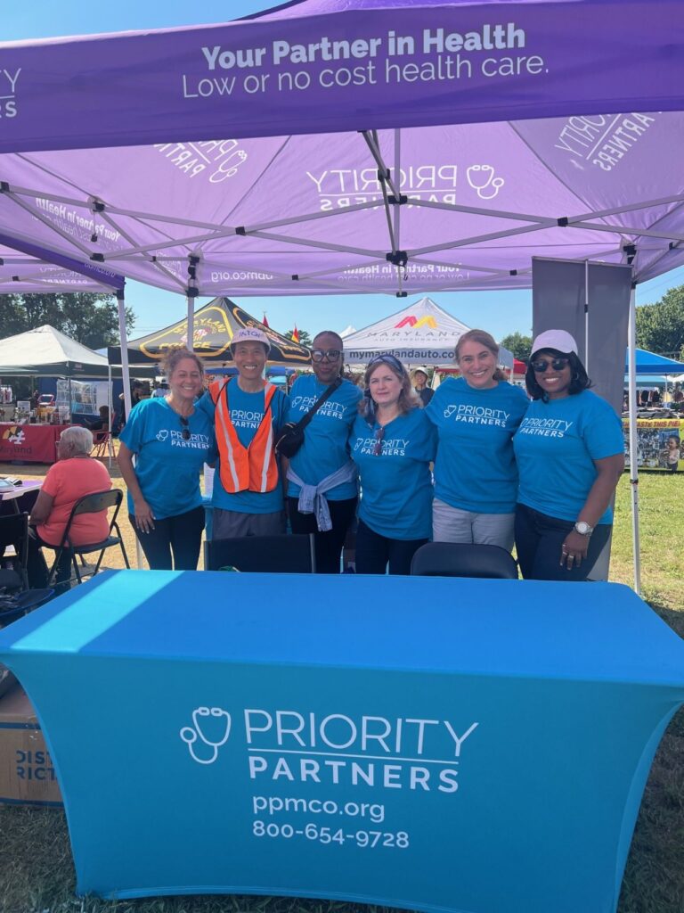group of community health advocates at en event pose for photo under tent