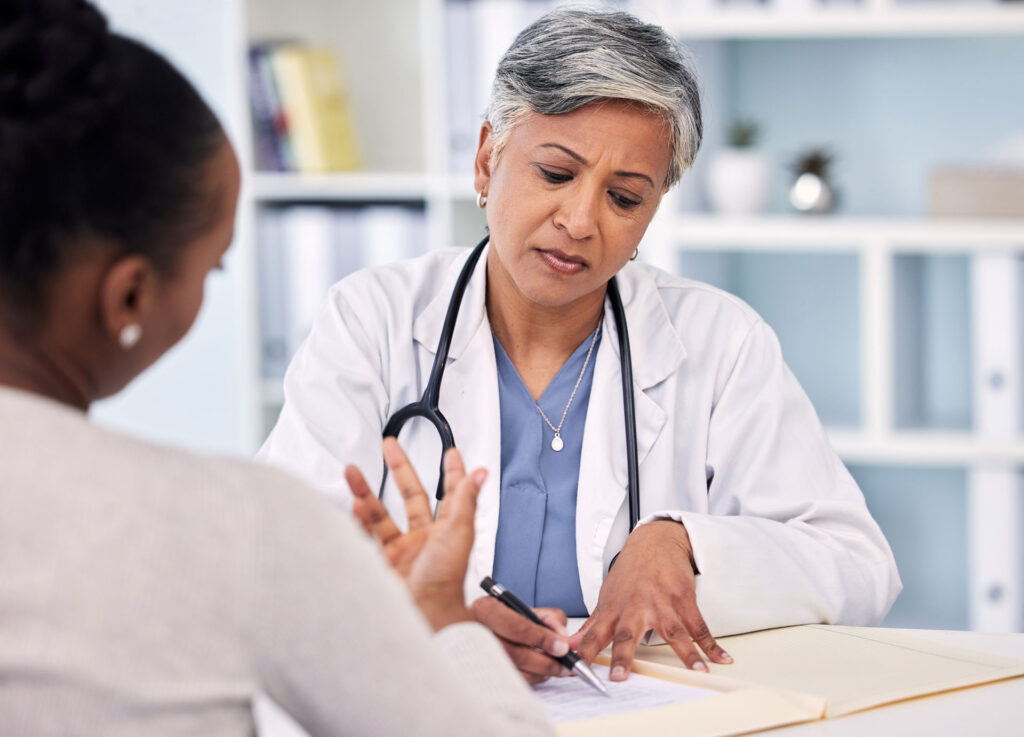 mature doctor sitting down with patient reviewing results